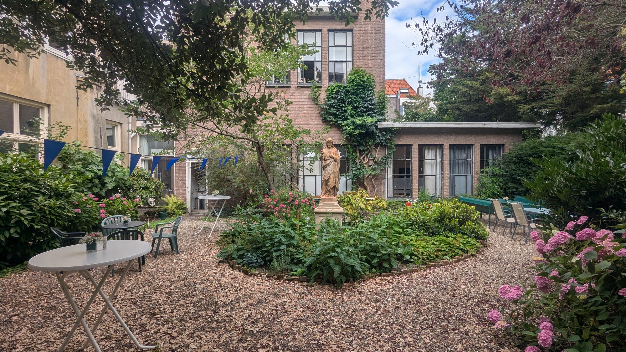 De kloostertuin met Mariabeeld en hortensia's